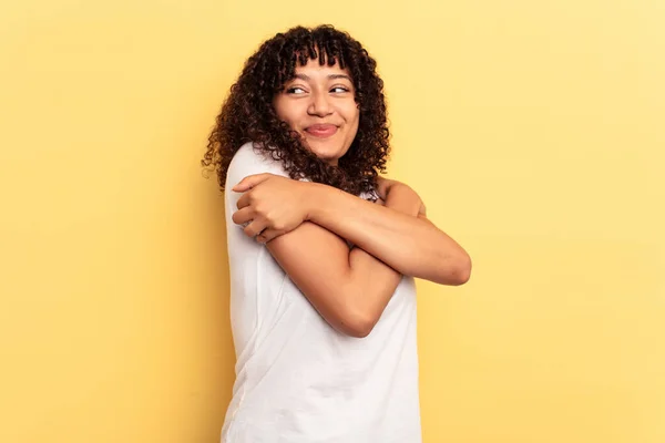 黄色の背景の抱擁に隔離された若い混合人種の女性は 屈託のない笑顔と幸せ — ストック写真