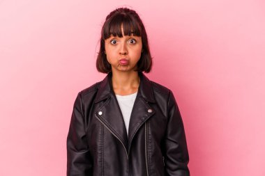 Pembe arka planda soyutlanmış genç melez bir kadın yanakları patlatıyor, yorgun bir ifadesi var. Yüz ifadesi kavramı.