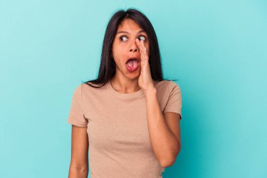 Mavi arka planda izole edilmiş genç Latin bir kadın heyecanla bağırıyor..