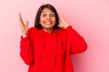 Pembe arka planda izole edilmiş genç Latin kadın öfkeyle bağırıyor..