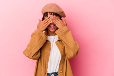 Pembe arka planda soyutlanmış genç bir ırk kadını elleriyle gözlerini kapatıyor, büyük bir gülümsemeyle bir sürpriz bekliyor..