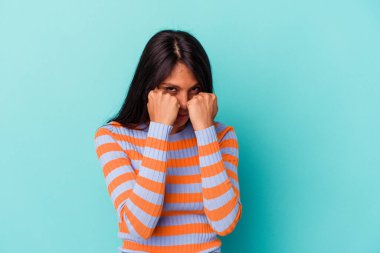 Mavi arka planda izole edilmiş genç Latin bir kadın bir tartışma yüzünden yumruk, öfke, kavga atıyor, boks yapıyor..