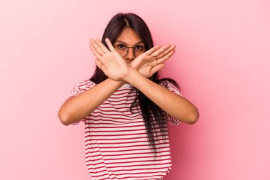 Pembe arka planda izole edilmiş genç Latin kadın inkar jesti yapıyor.