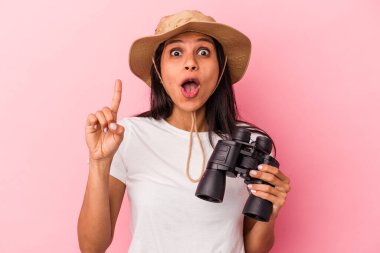 Dürbün tutan genç Latin kadın pembe arka planda izole edilmiş harika bir fikri var, yaratıcılık kavramı..