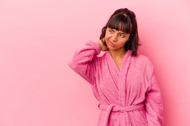 Pembe arka planda bornoz giyen genç melez bir kadın kafasının arkasına dokunuyor, düşünüyor ve bir seçim yapıyor..