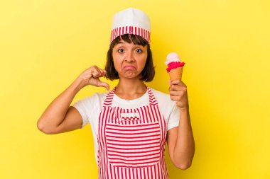 Sarı arka planda izole edilmiş dondurma tutan genç melez dondurma üreticisi kadın gururlu ve kendinden emin, örnek olarak.