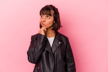 Genç melez kadın pembe arka planda izole edilmiş düşünüyor, bakıyor, yansıtıyor, düşünüyor, fantezi kuruyor..