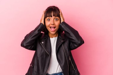 Genç melez kadın pembe arka planda izole edilmiş bağırıyor, çok heyecanlı, tutkulu, bir şeyden memnun..