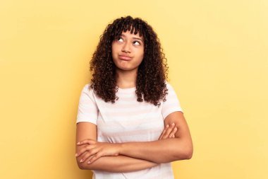 Sarı arka planda izole edilmiş genç melez kadın tekrarlanan bir görevden yoruldu..