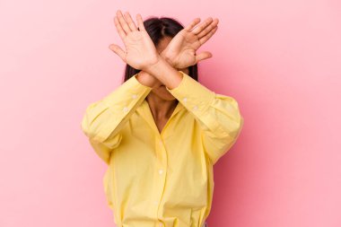 Pembe arka planda izole edilmiş genç Latin kadın iki kolu çapraz tutuyor, inkar kavramı.