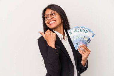 Beyaz arka planda banknotları tutan genç Latin bir kadın. Baş parmak uzakta, gülüyor ve kaygısız..