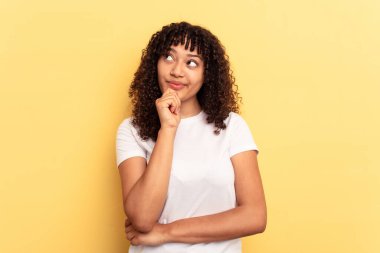Sarı arka planda izole edilmiş genç bir ırk kadını rahat bir şekilde fotokopi odasına bakan bir şeyi düşünüyor..