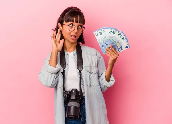 若い混合人種の写真家の女性はピンクの背景に孤立した法案を保持しますゴシップを聞こうと — ストック写真