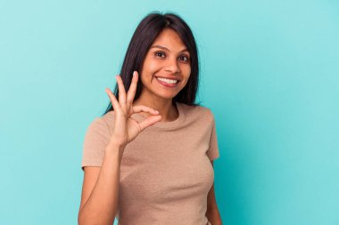 Genç Latin bir kadın mavi arka planda izole edilmiş neşeli ve kendinden emin..