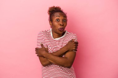 Genç Afrikalı Amerikalı kadın pembe arka planda izole edilmiş omuzlarını silkeliyor ve gözleri açık..