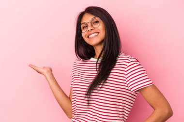 Pembe arka planda izole edilmiş genç Latin kadın hoş bir yüz ifadesi sergiliyor..