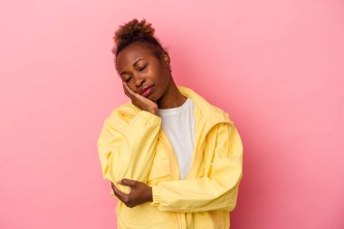 Pembe arka planda izole edilmiş, sıkılmış, yorgun ve dinlenmeye ihtiyacı olan genç Afrikalı Amerikalı kadın..
