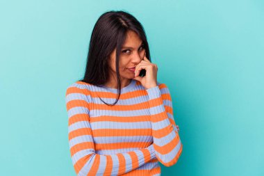 Genç Latin bir kadın mavi arka planda izole edilmiş. Bir strateji planlıyor, bir iş yolu düşünüyor..