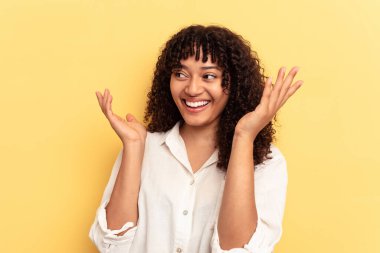 Genç melez kadın sarı arka planda izole edilmiş neşeli bir şekilde gülüyor. Mutluluk kavramı.