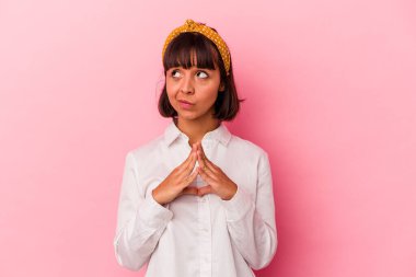 Genç melez kadın pembe arka planda izole edilmiş dua ediyor, bağlılık gösteriyor, dindar biri ilahi ilham arıyor..