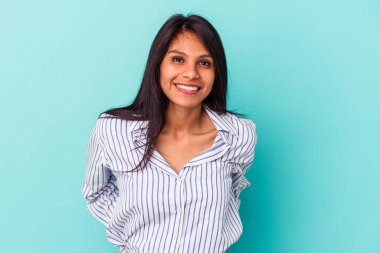 Mavi arka planda izole edilmiş genç Latin kadın mutlu, güler yüzlü ve neşeli..