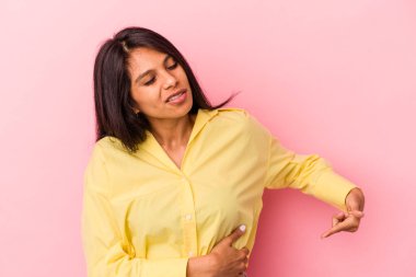 Pembe arka planda karaciğer ağrısı ve karın ağrısı çeken genç Latin bir kadın..