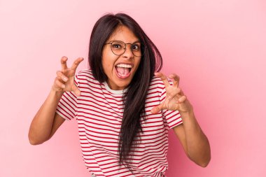 Pembe arka planda izole edilmiş genç Latin kadın gergin ellerle çığlık atıyor..