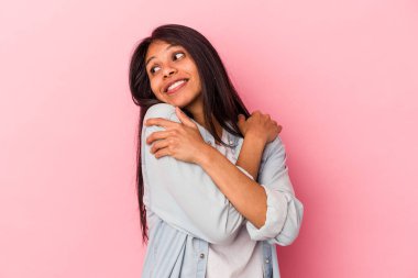 Genç Latin kadın pembe arka planda izole edilmiş. Kucaklaşma, kaygısız gülümseme ve mutluluk..