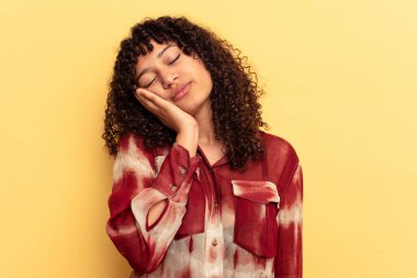 Sarı arka planda soyutlanmış, sıkılmış, yorgun ve dinlenmeye ihtiyacı olan genç melez bir kadın..