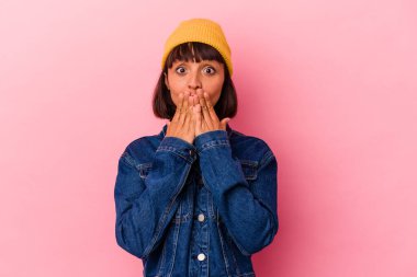 Pembe arka planda izole edilmiş genç bir ırk kadını elleriyle ağzını kapatırken şok oldu..