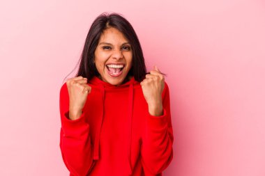 Pembe arka planda izole edilmiş genç Latin kadın gergin ellerle çığlık atıyor..