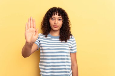 Sarı arka planda izole edilmiş genç, melez bir kadın elini uzatmış, dur işareti göstererek seni engelliyor..