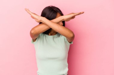 Pembe arka planda izole edilmiş genç Latin kadın iki kolu çapraz tutuyor, inkar kavramı.