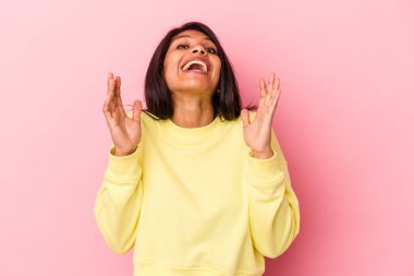 Pembe arka planda izole edilmiş genç Latin kadın yüksek sesle gülüyor elini göğsüne koyuyor..