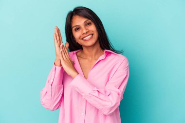 Mavi arka planda izole edilmiş genç Latin kadın enerjik ve rahat hissediyor, ellerini ovuşturuyor..