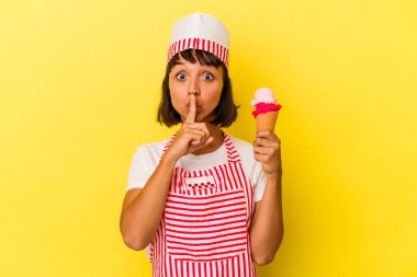 Genç melez dondurma üreticisi kadın dondurma tutuyor sarı arka planda izole edilmiş bir şekilde ya sır saklıyor ya da sessizlik istiyor..