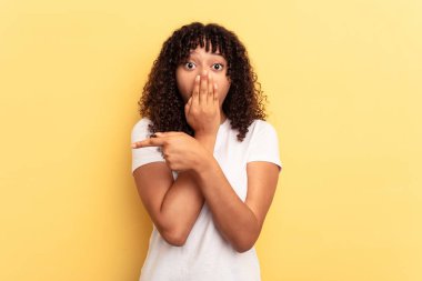 Sarı arka planda izole edilmiş genç, melez bir kadın.