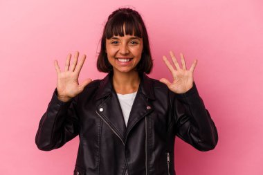 Pembe arka planda izole edilmiş genç melez kadın on numarayı elleriyle gösteriyor..