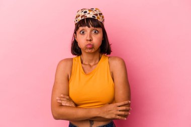 Pembe arka planda soyutlanmış genç melez bir kadın yanakları patlatıyor, yorgun bir ifadesi var. Yüz ifadesi kavramı.