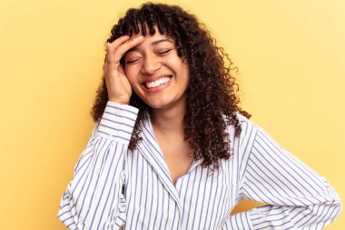 Genç melez kadın sarı arka planda izole edilmiş neşeli bir şekilde gülüyor. Mutluluk kavramı.