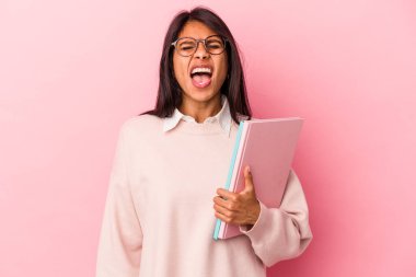 Pembe arka planda izole edilmiş genç Latin kadın çok sinirli ve agresif bağırıyor..