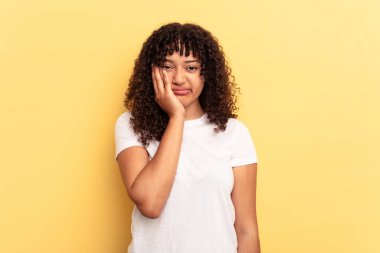Sarı arka planda soyutlanmış, üzgün ve dalgın hisseden, kopyalama alanına bakan genç melez bir kadın..