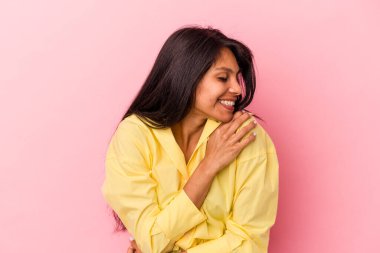 Genç Latin bir kadın pembe arka planda izole edilmiş gülüyor ve eğleniyor..