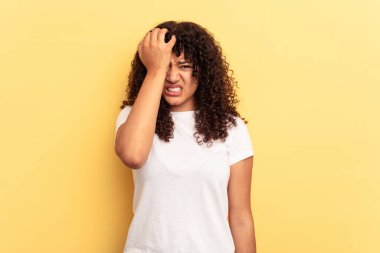 Sarı arka planda izole edilmiş genç bir ırk kadını bir şeyi unutuyor, alnına avuç içi ile vuruyor ve gözlerini kapatıyor..