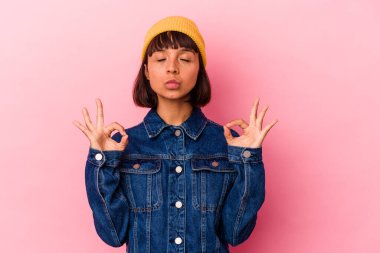 Pembe arka planda soyutlanmış genç melez kadın yoğun bir günün ardından rahatlıyor, yoga yapıyor..