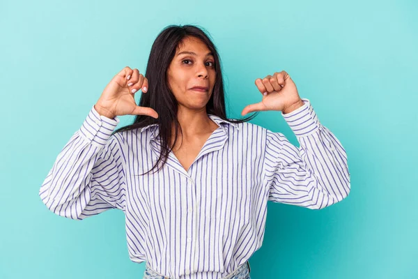 Mavi arka planda soyutlanmış genç Latin kadın gururlu ve kendinden emin hissediyor, örnek olarak..