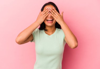 Young Venezuelan woman isolated on pink background covers eyes with hands, smiles broadly waiting for a surprise. clipart