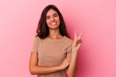 Pembe arka planda izole edilmiş genç beyaz kadın iki numarayı parmaklarıyla gösteriyor..