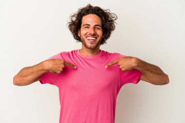 Beyaz arka planda izole edilmiş genç beyaz bir adam parmağını göstererek şaşırdı, geniş bir gülümsemeyle..