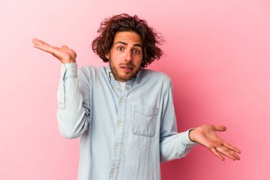 Kafkasyalı genç bir adam pembe fırında izole edilmiş. Kafası karışmış ve omuz silkiyor. Kopya alanını tutmak için..